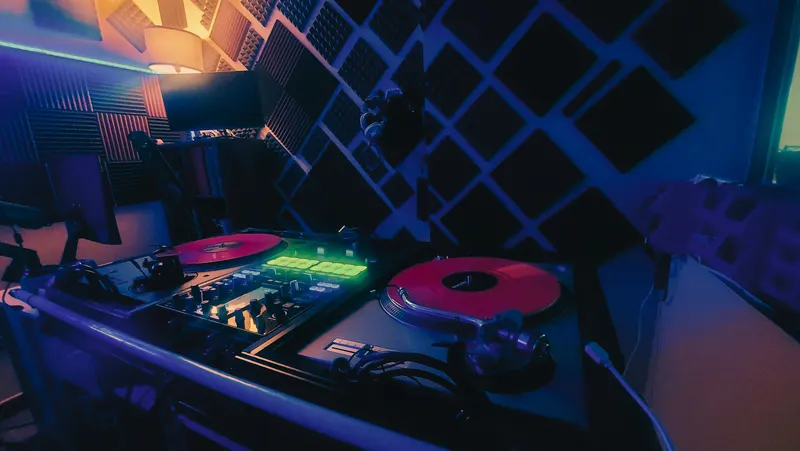 Platos con vinilos rojos y mesa de mezclas iluminada en el estudio